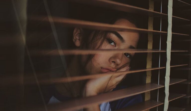 depressed enfp woman looking behind the curtains