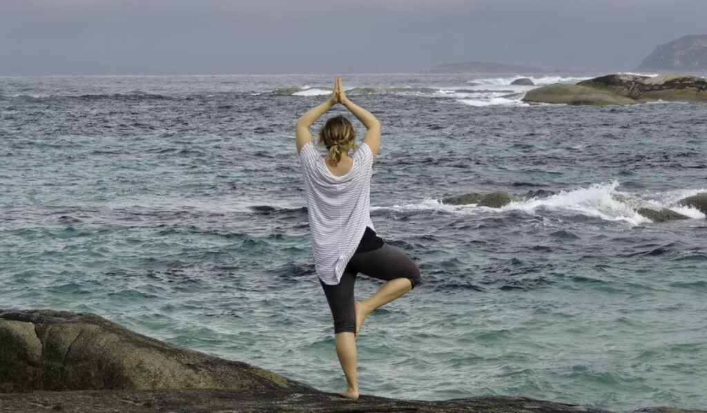 taurus woman doing yoga by the beach