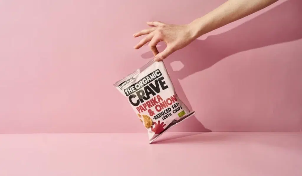 woman holding a snack on a pink background