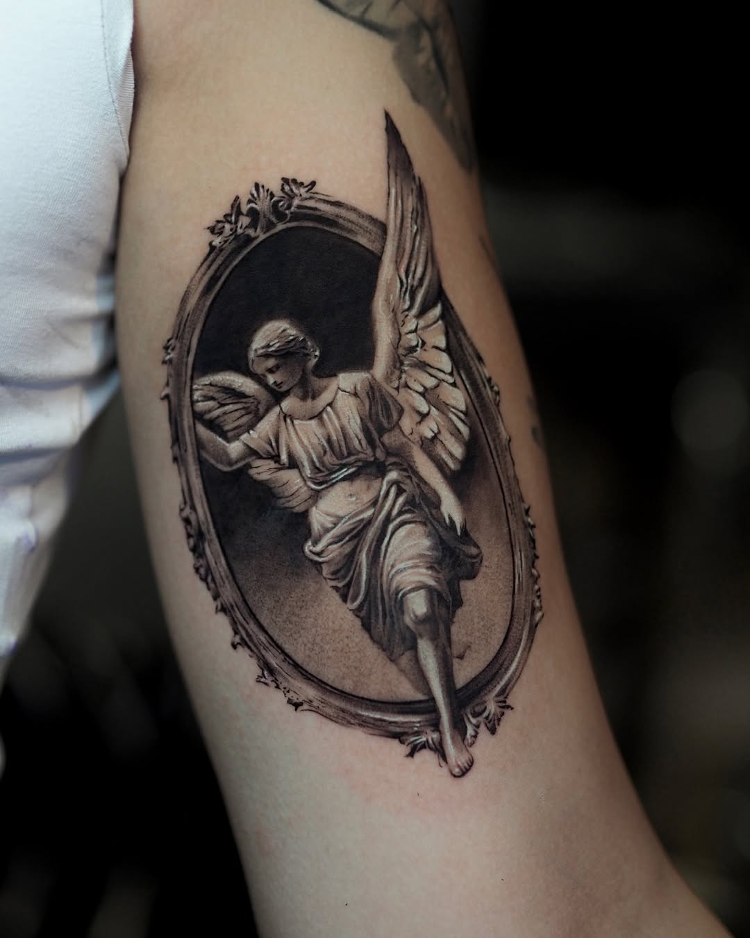 Realistic angel tattoo framed in ornate design