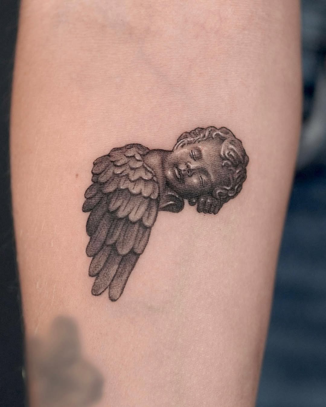 Intricate cherub tattoo with soft feathered wings