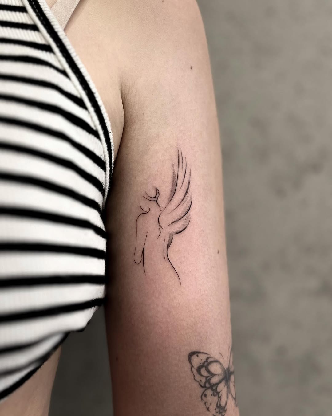 Minimalist angel wing tattoo on the arm