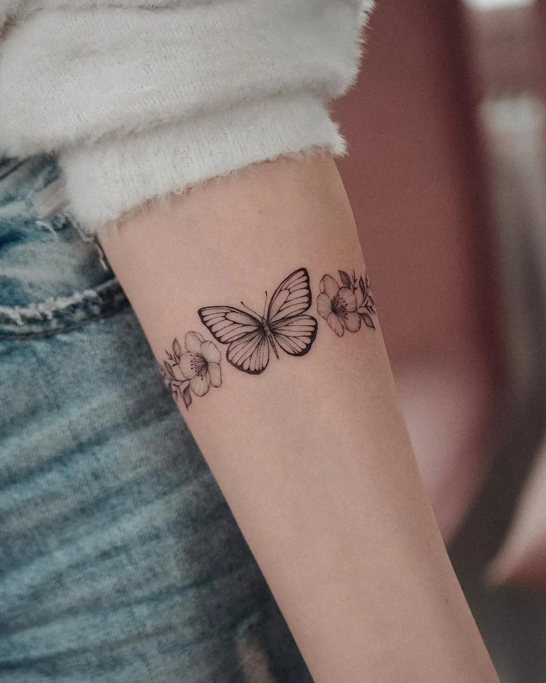 Elegant butterfly bracelet tattoo with floral accents