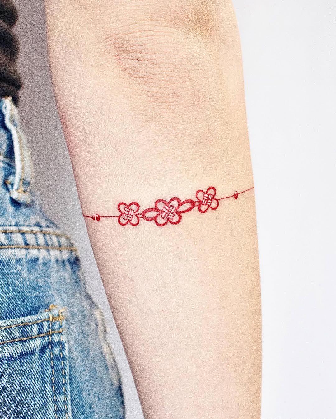 Elegant red flower bracelet tattoo on arm