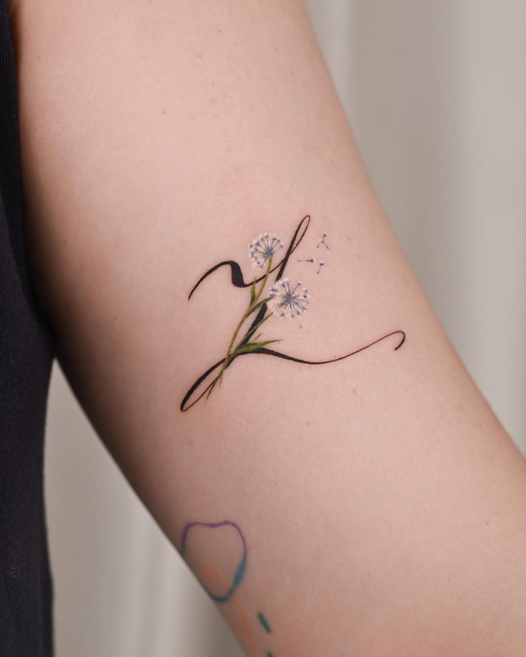 Elegant dandelion tattoo with flowing script