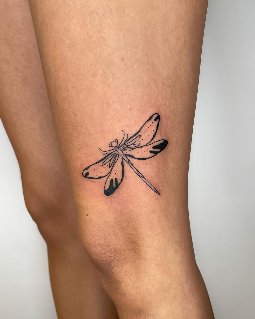 Detailed black ink dragonfly tattoo on leg