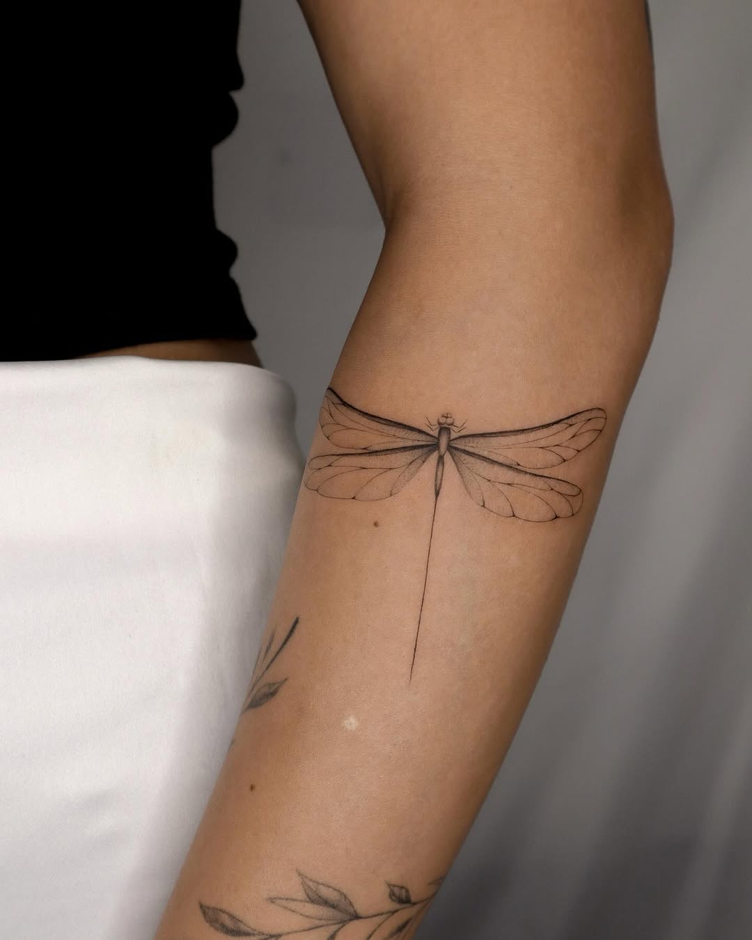 Elegant black ink dragonfly tattoo on arm