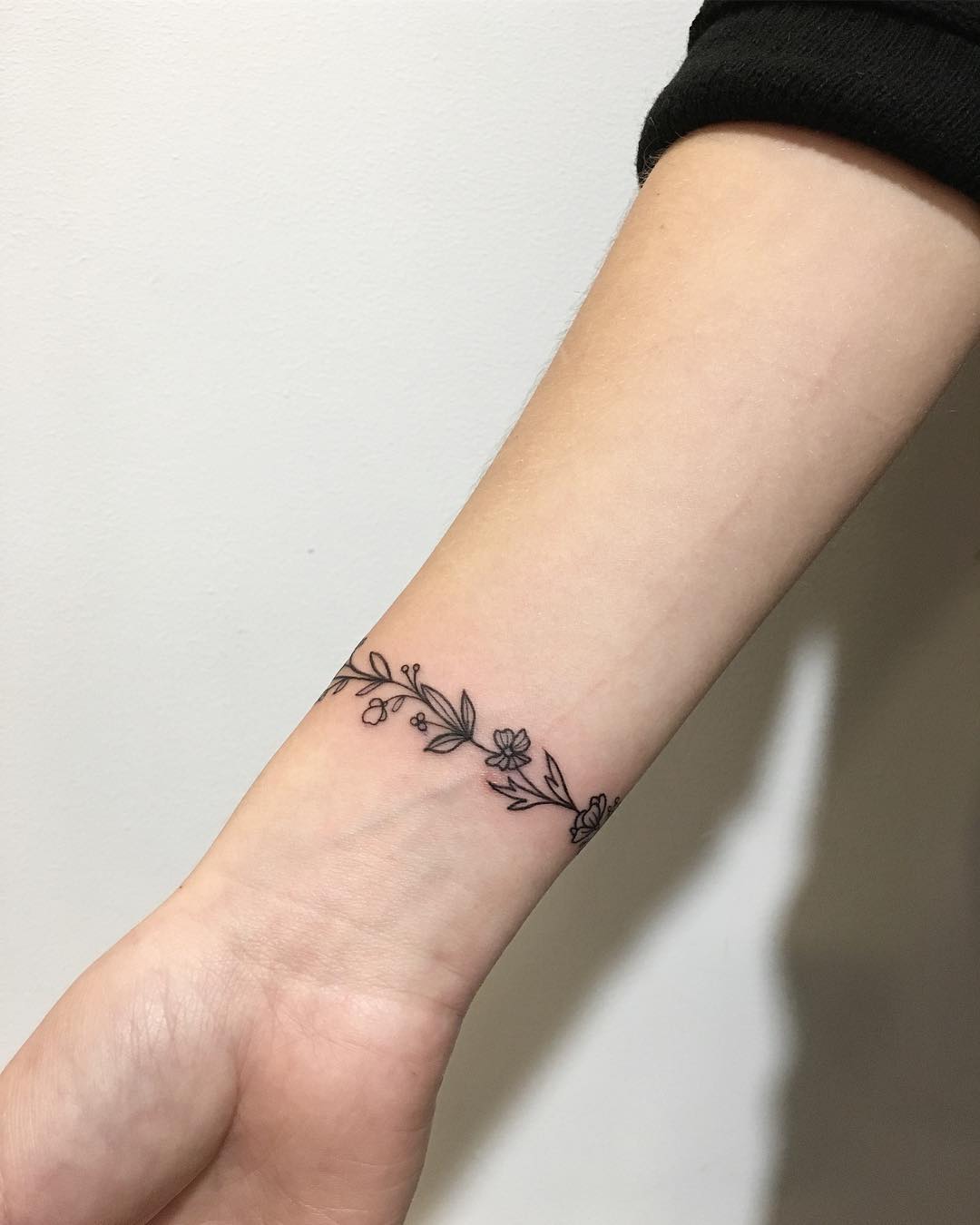 Elegant floral bracelet tattoo on the arm