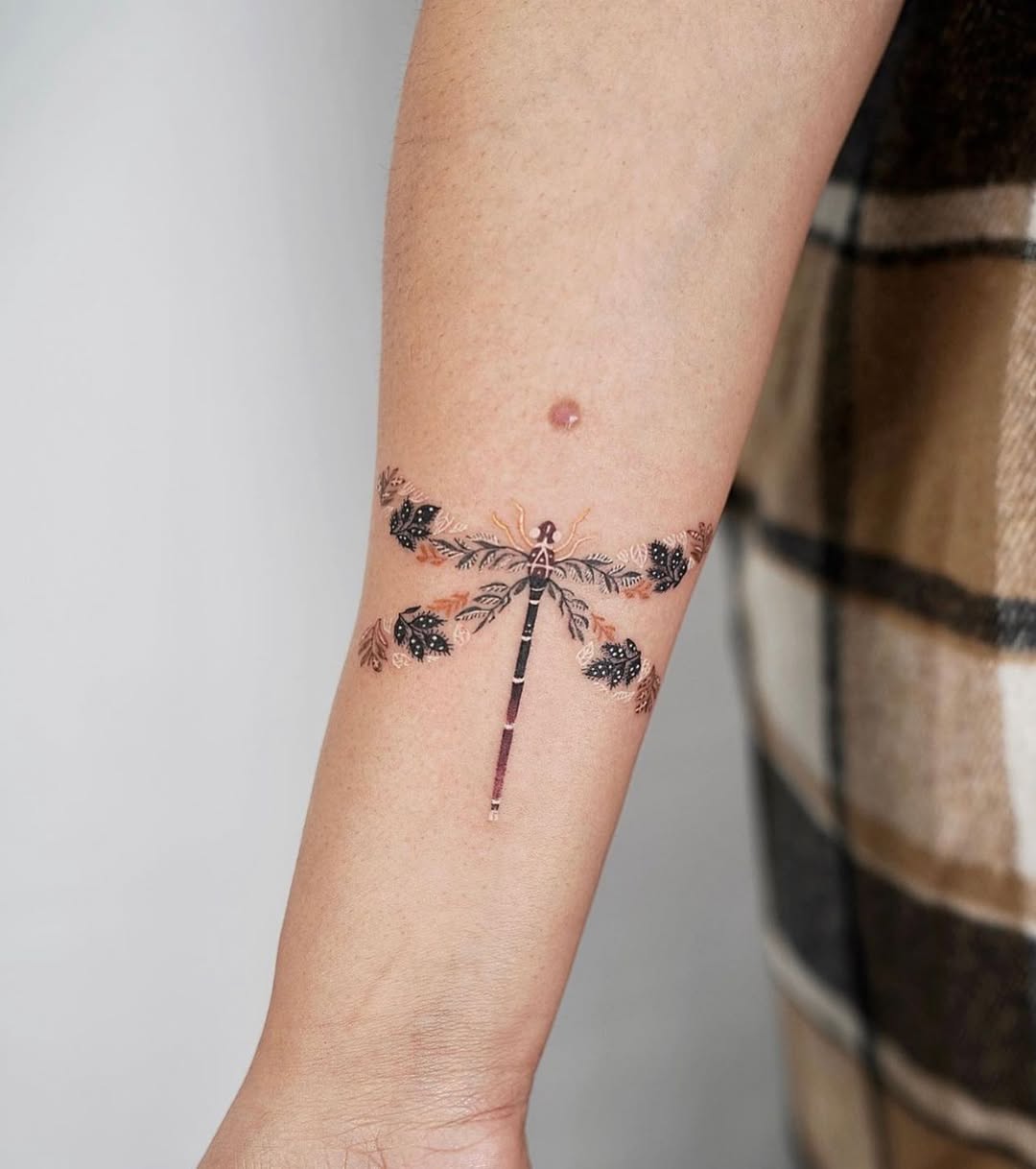 Elegant dragonfly tattoo with floral accents