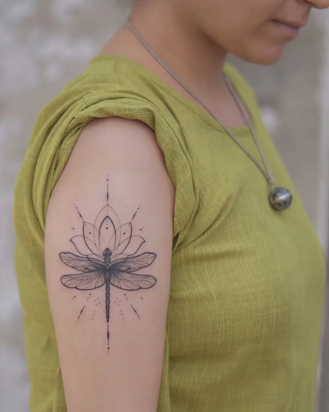 Intricate dragonfly and lotus tattoo on arm