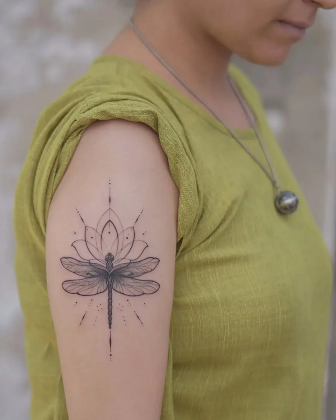 Intricate dragonfly and lotus tattoo on arm