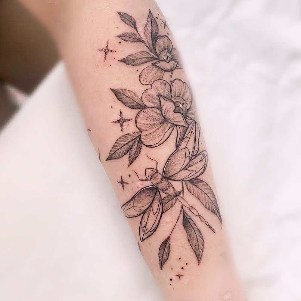 Delicate dragonfly tattoo with floral accents