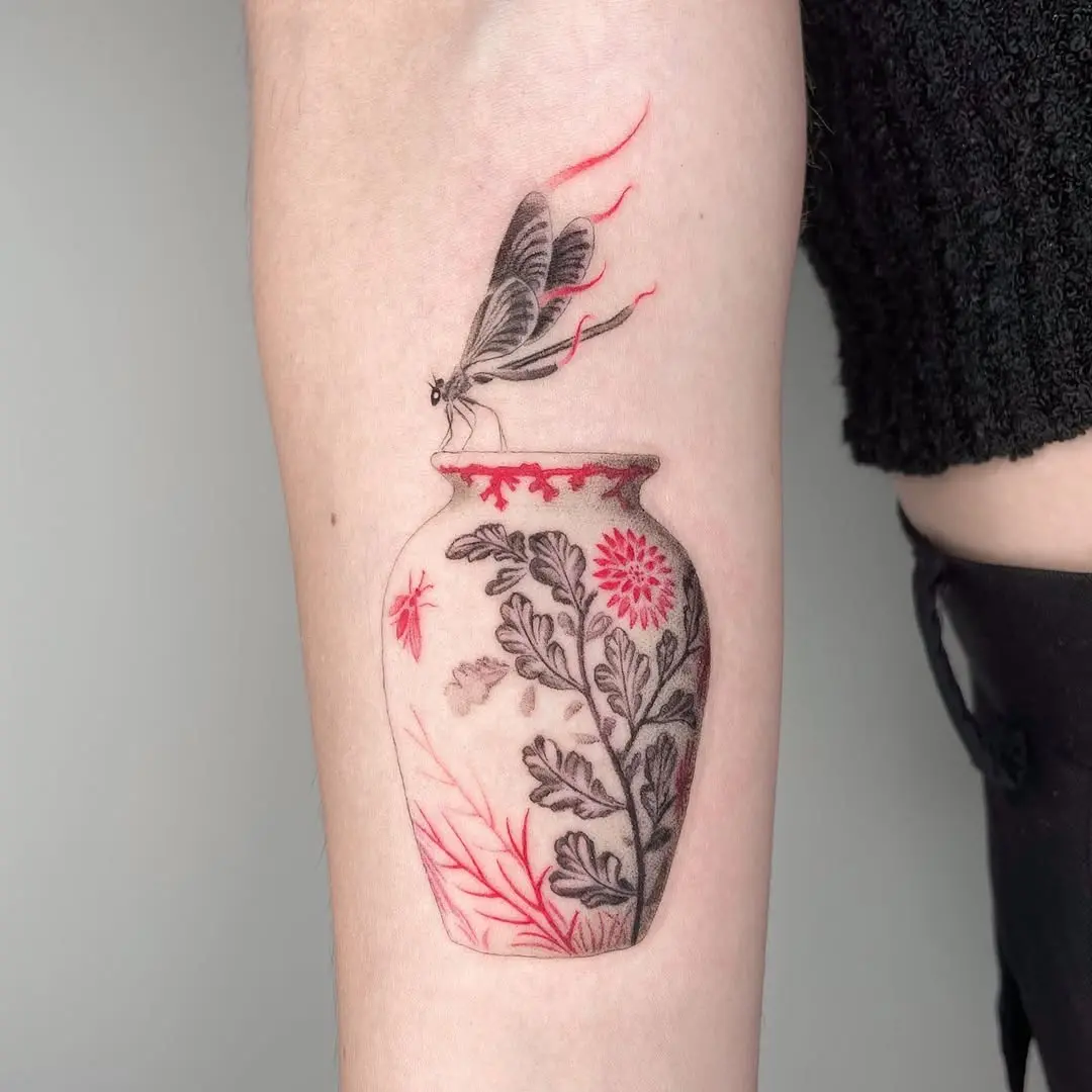 Intricate dragonfly tattoo with floral vase design