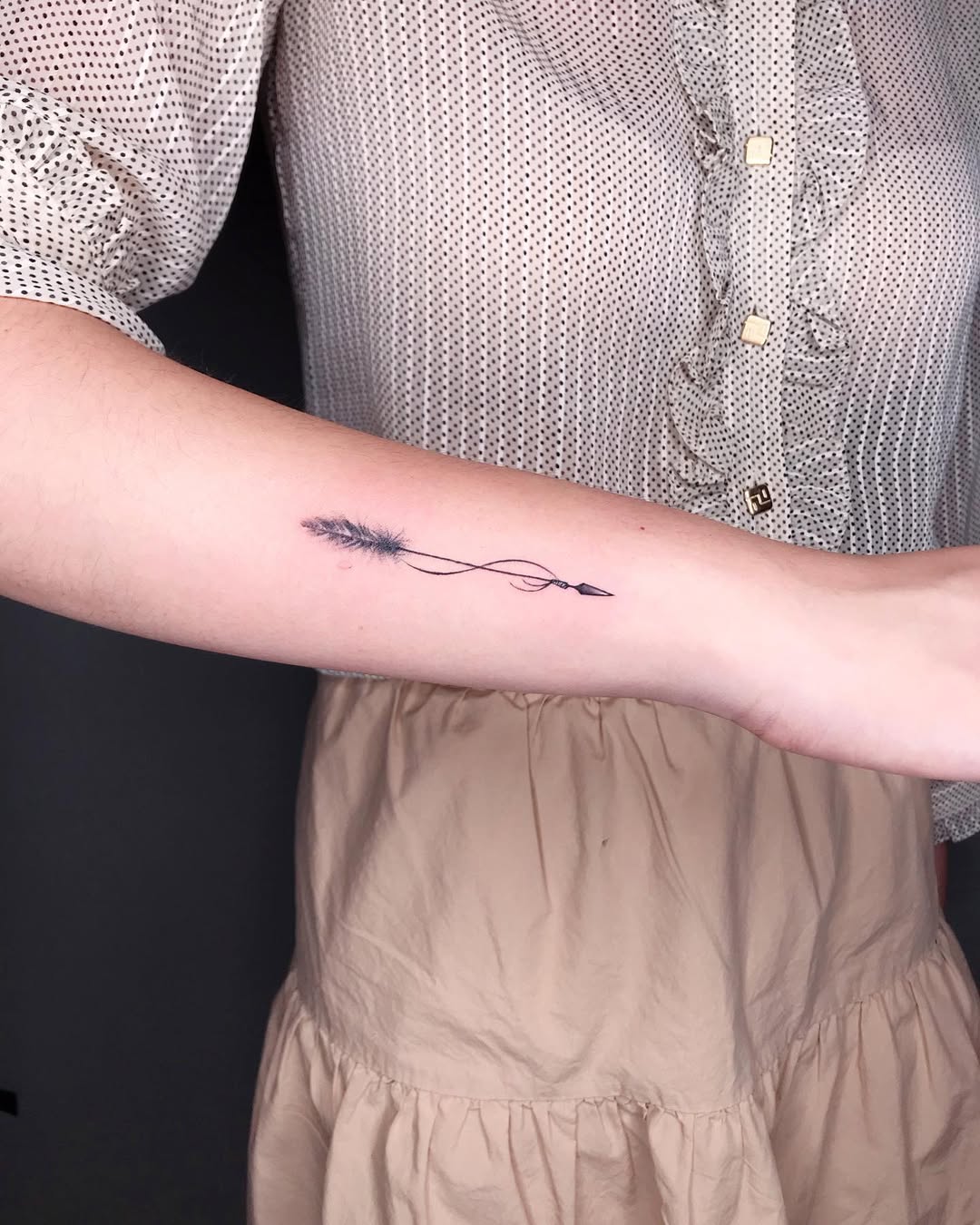 Delicate arrow tattoo with a feather design