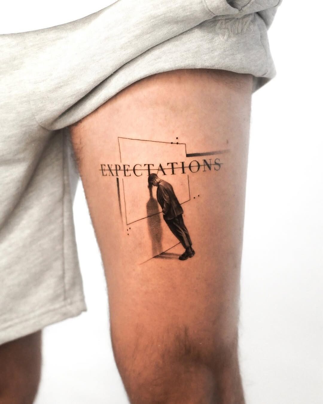 Intriguing expectations tattoo on thigh