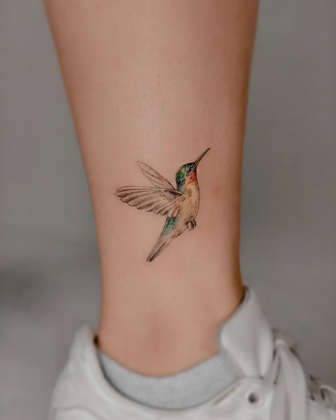 Vibrant hummingbird tattoo on ankle design