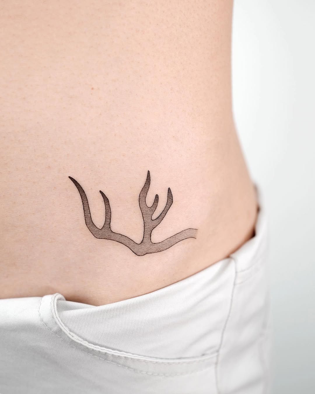 Elegant minimalist antler tattoo on the side