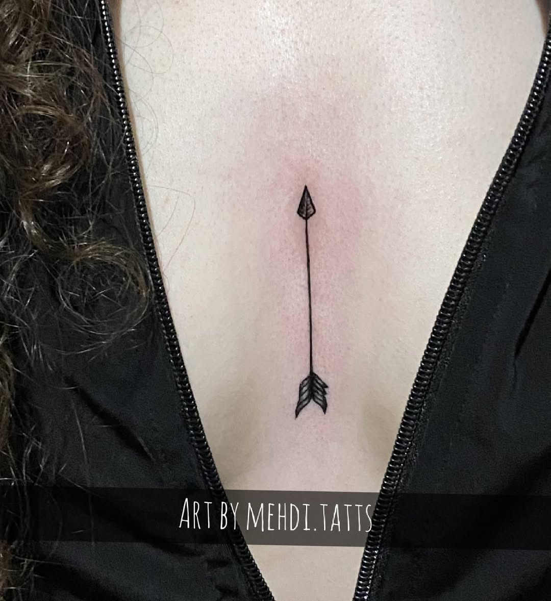 Elegant minimalist arrow tattoo under collarbone