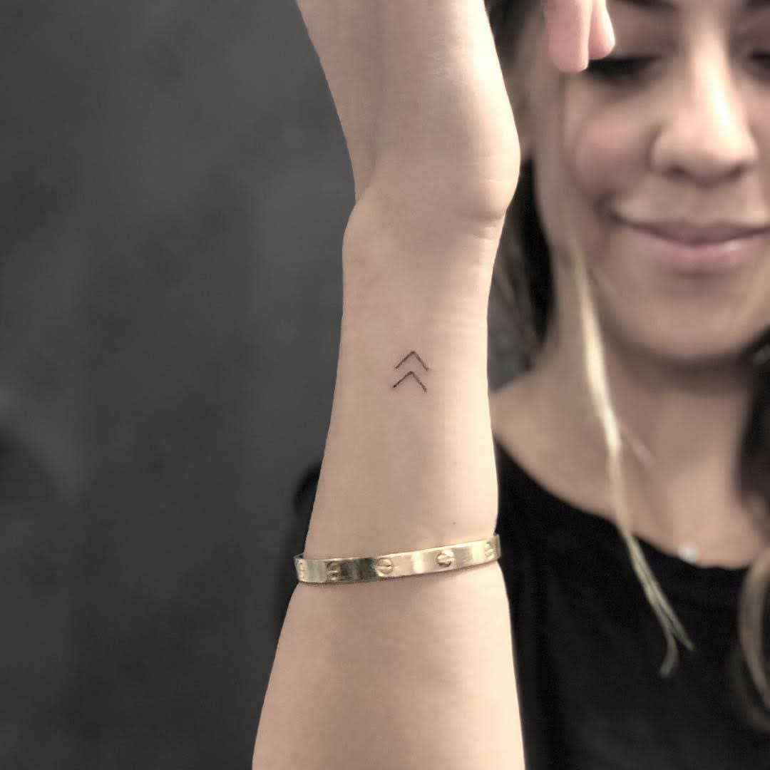 Stylish minimalist arrow tattoo on wrist