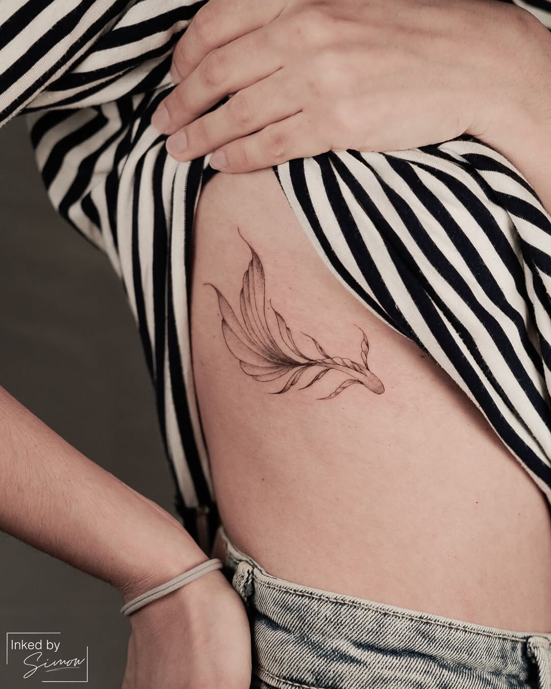 Elegant Rib Tattoo of a Feather Design