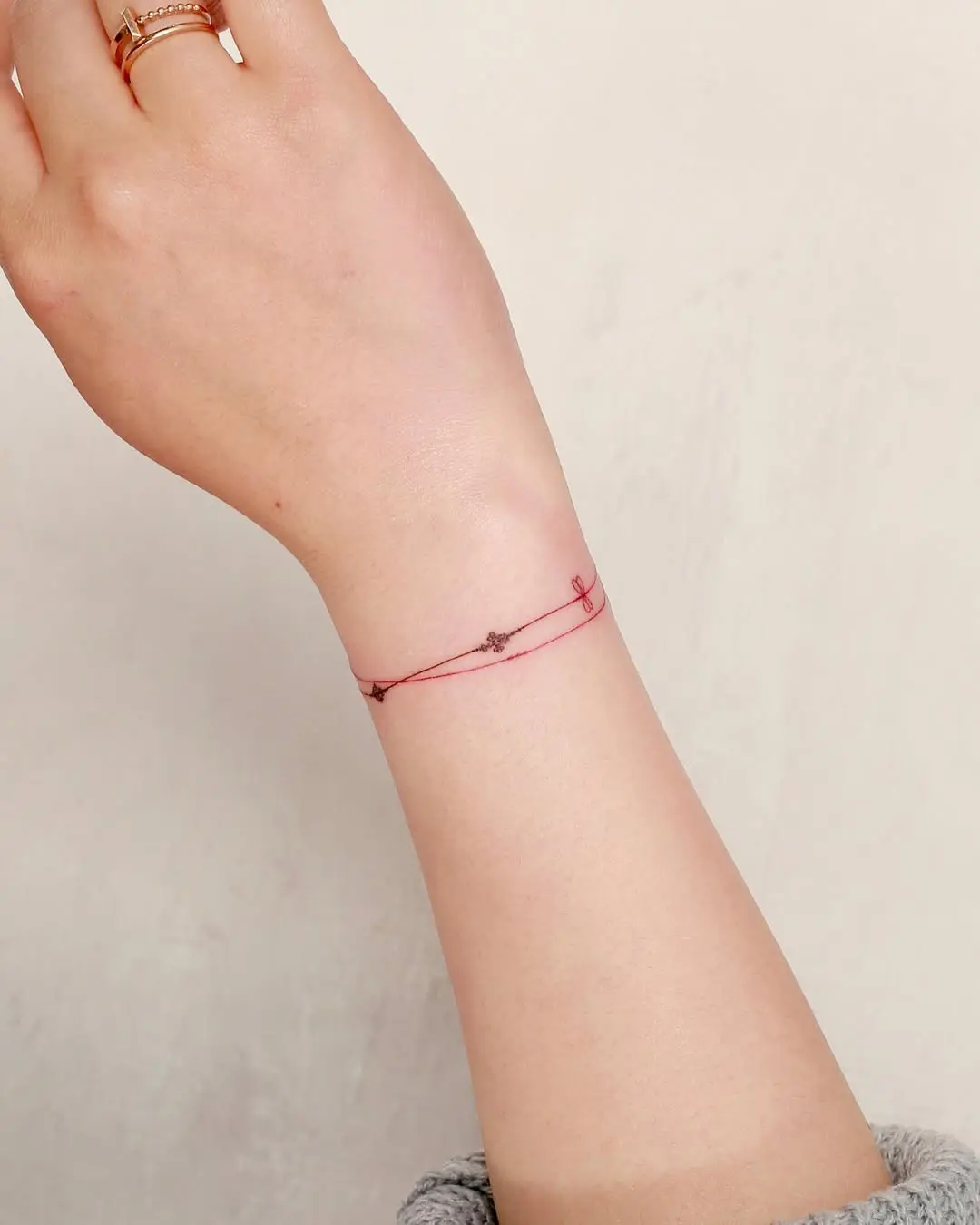Minimalist red line bracelet tattoo design