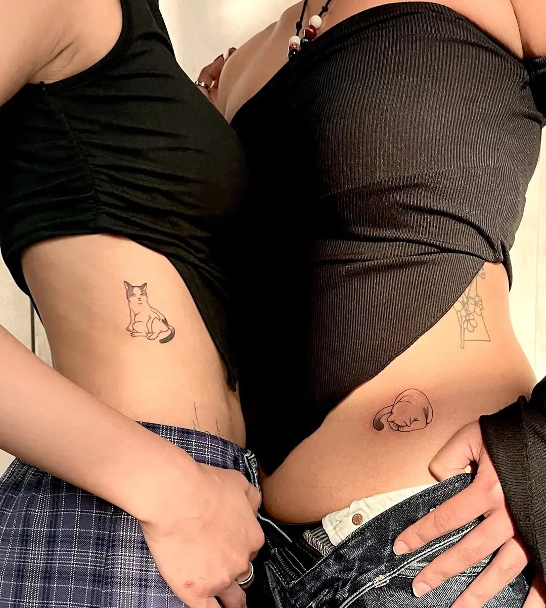 Charming sister tattoos featuring playful cat designs