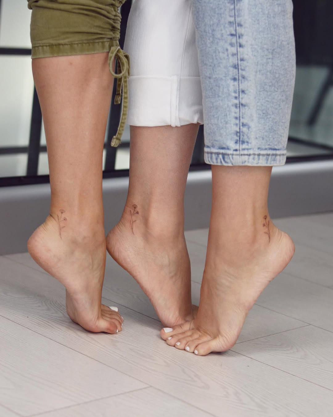 Delicate floral tattoos on sister's ankles