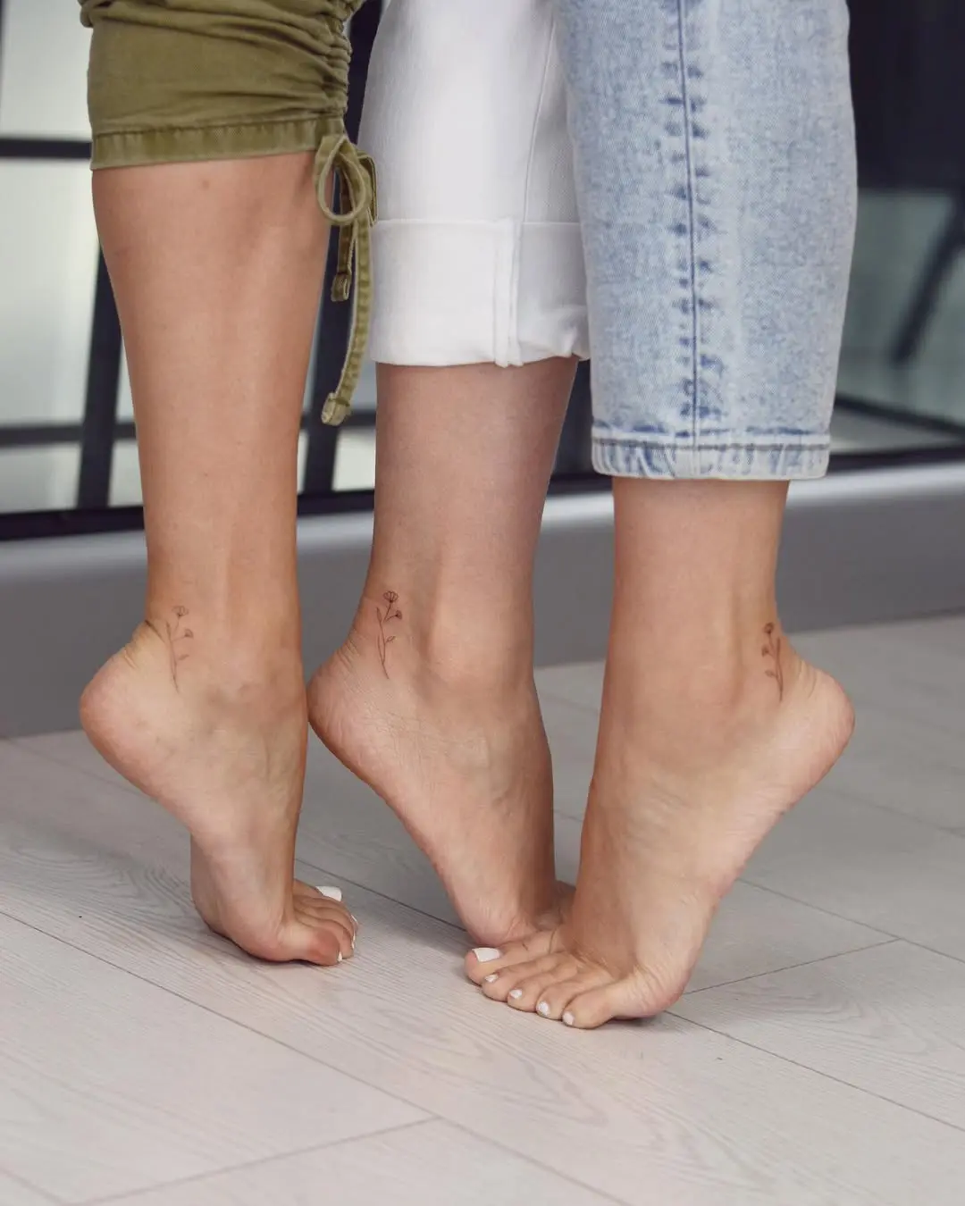 Delicate floral tattoos on sister's ankles