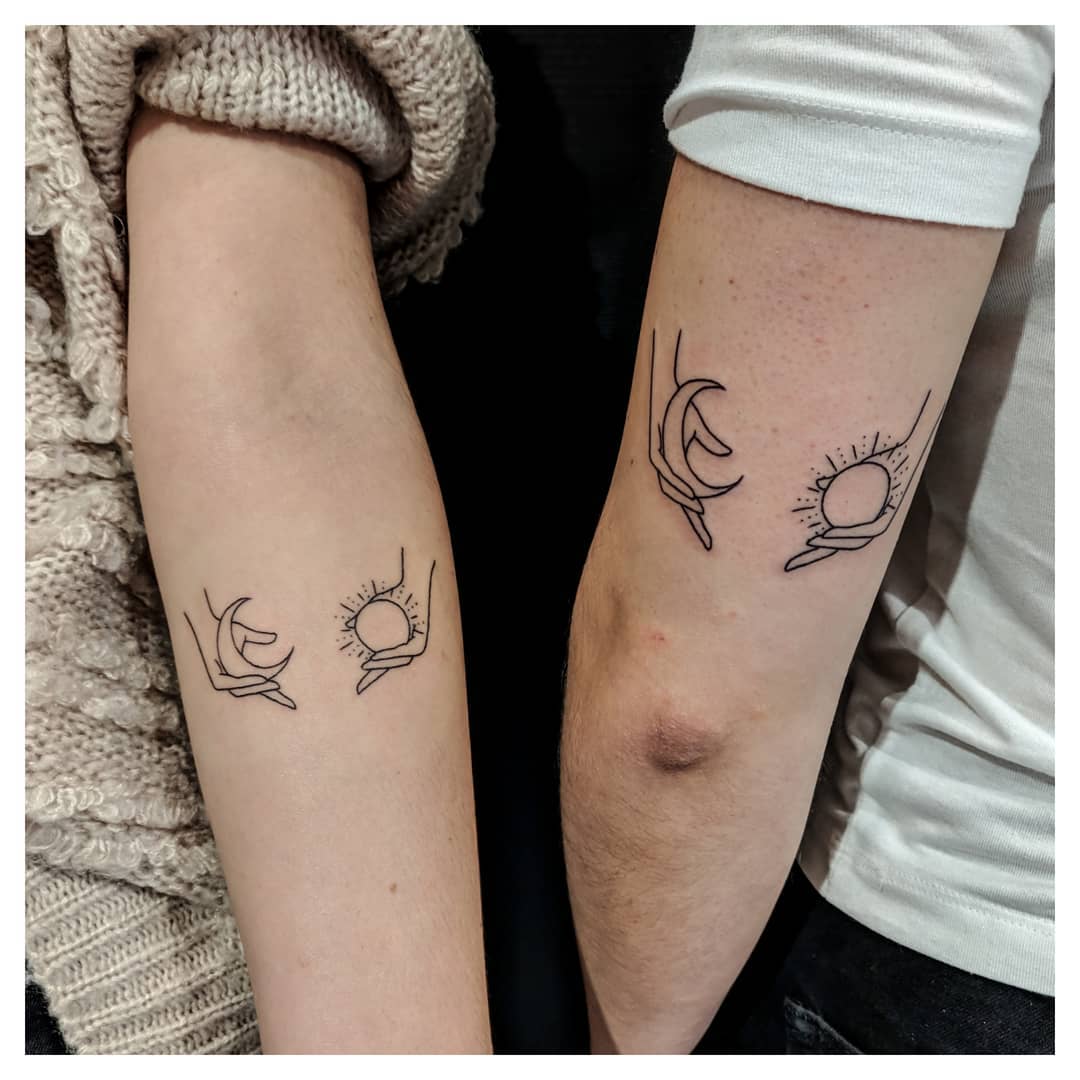 Minimalist hands holding sun and moon tattoos