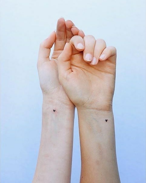 Minimalist heart tattoos for sisters' bond