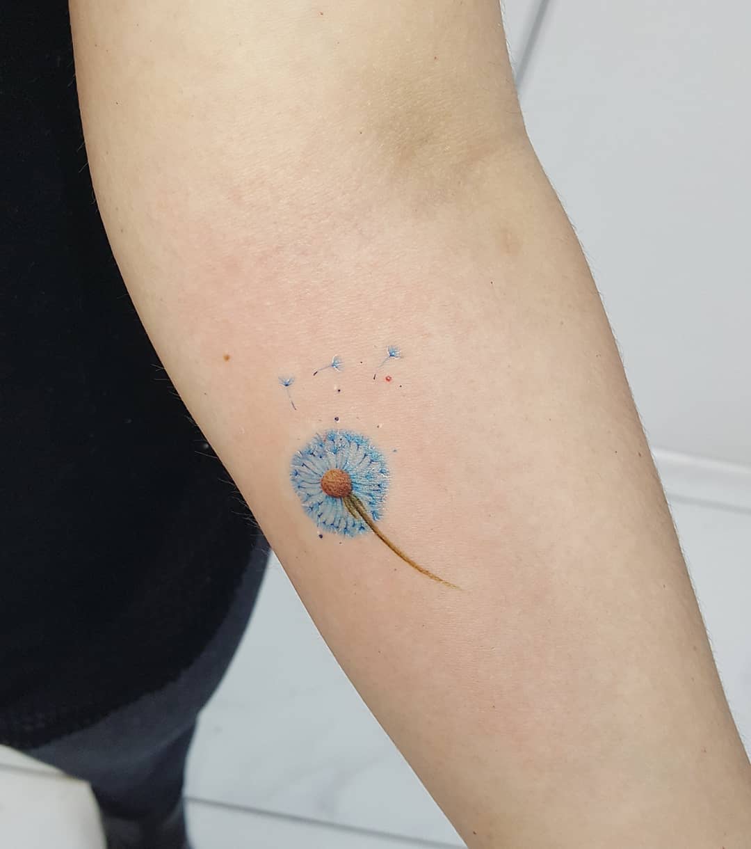 Vibrant blue dandelion tattoo on the arm