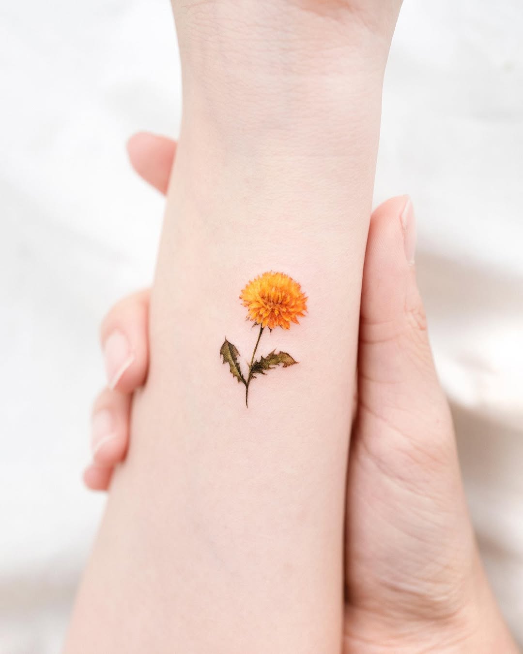 Bright orange dandelion tattoo with subtle details