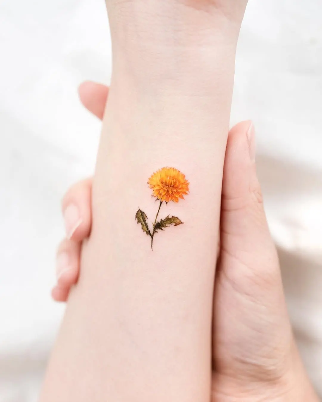 Bright orange dandelion tattoo with subtle details