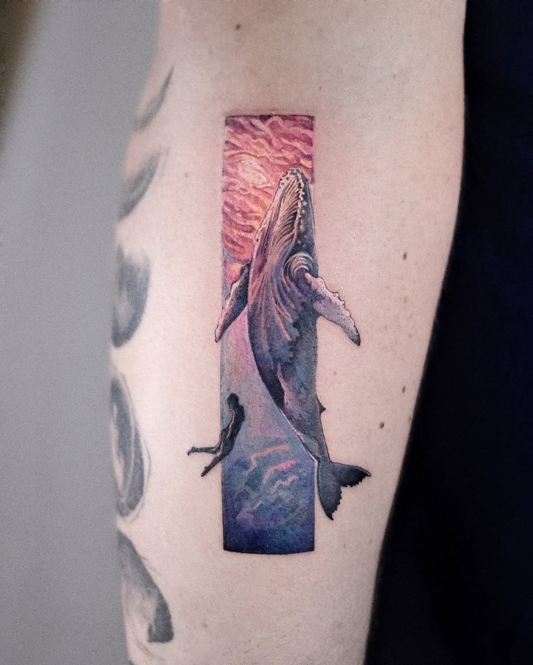 Vibrant whale tattoo with dreamy ocean backdrop