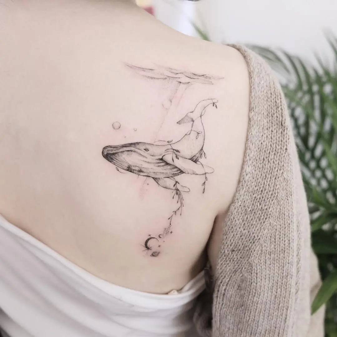 Elegant minimalist whale tattoo on shoulder