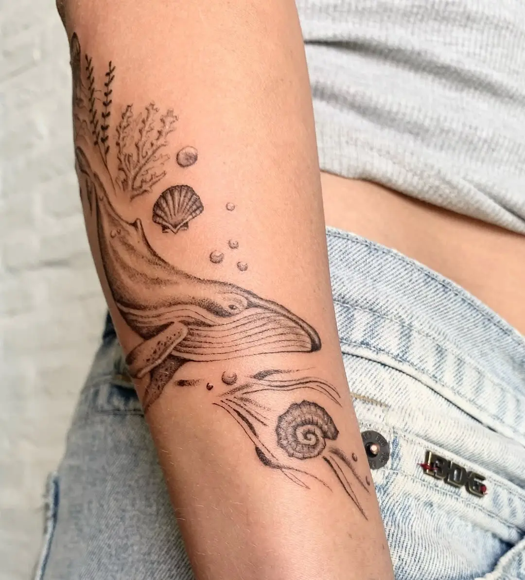 Elegant minimalist whale tattoo on the arm.