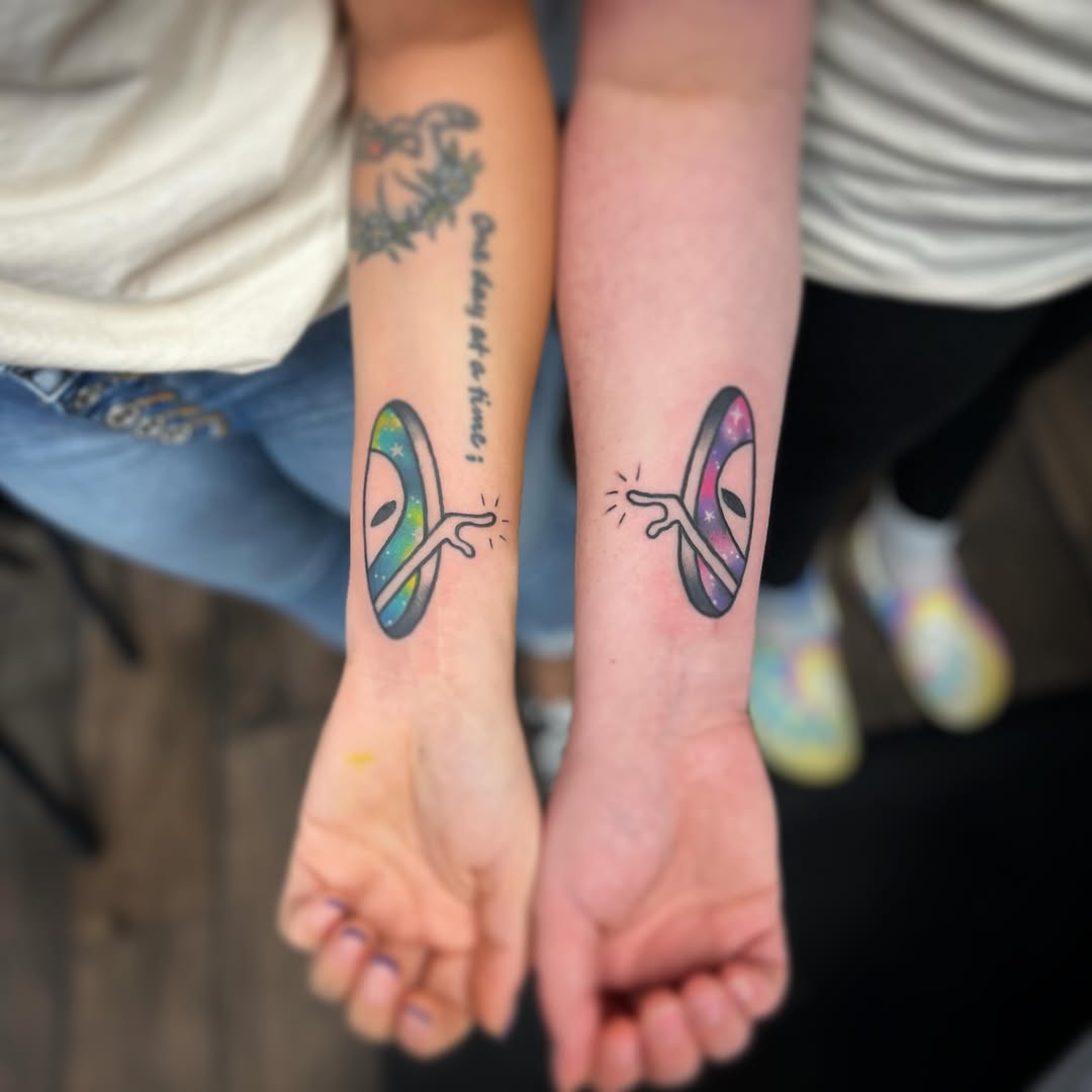 Colorful alien tattoos connecting two friends