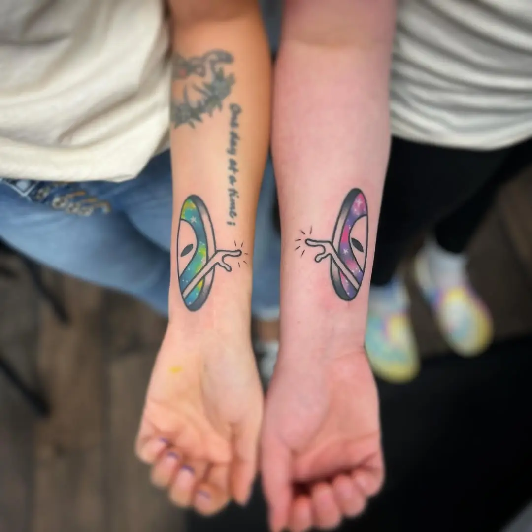 Colorful alien tattoos connecting two friends