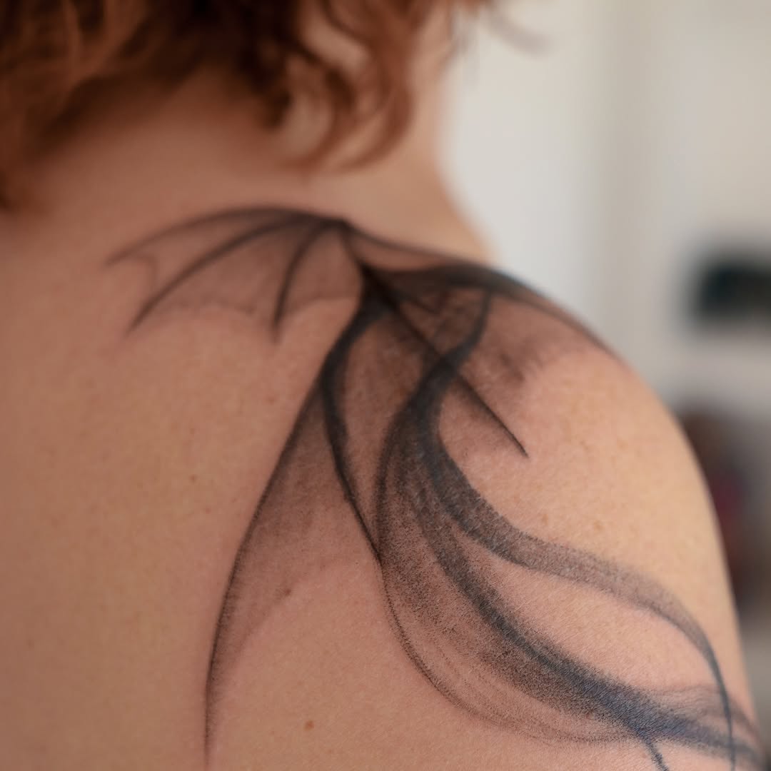 Elegant dragon silhouette tattoo on shoulder