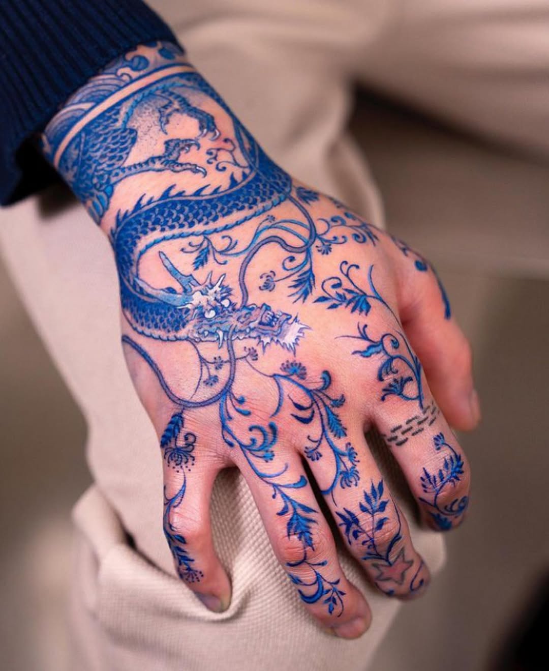 Intricate blue dragon tattoo on hand.