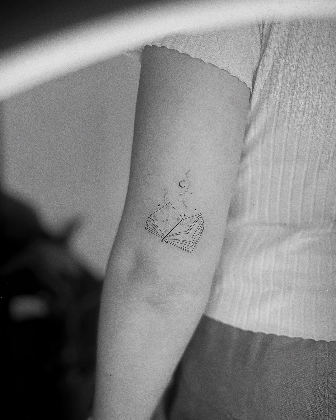 Charming minimalist book tattoo on the arm