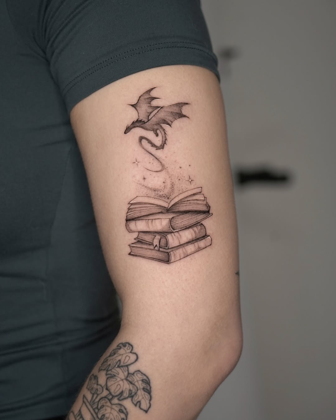 Whimsical bat over stacked open books tattoo