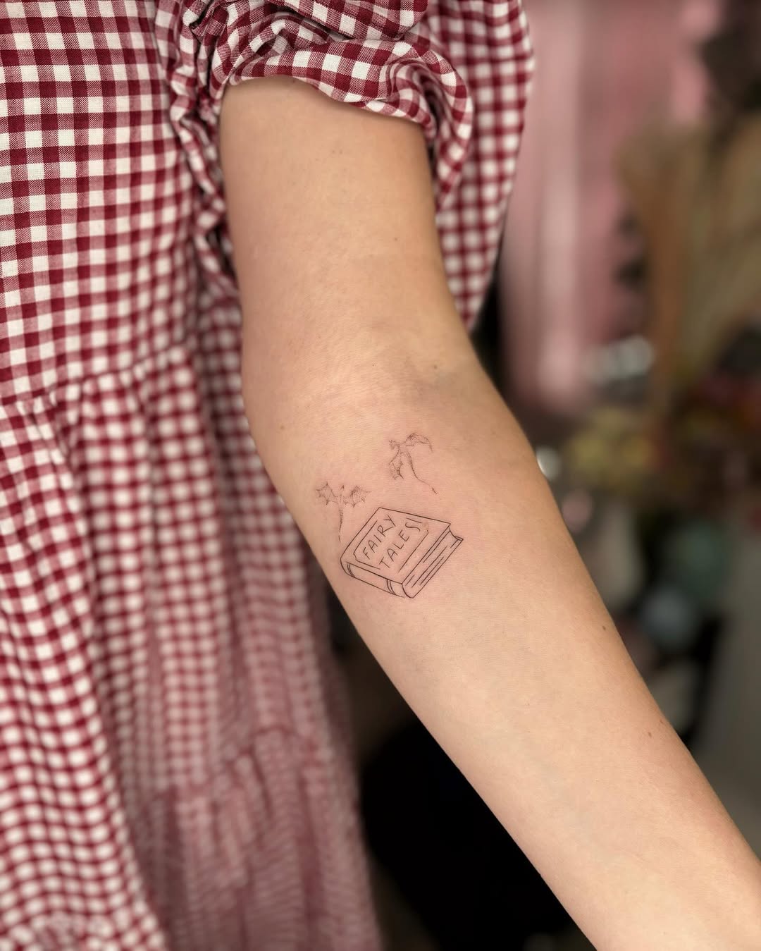 Charming minimalist book tattoo design on arm