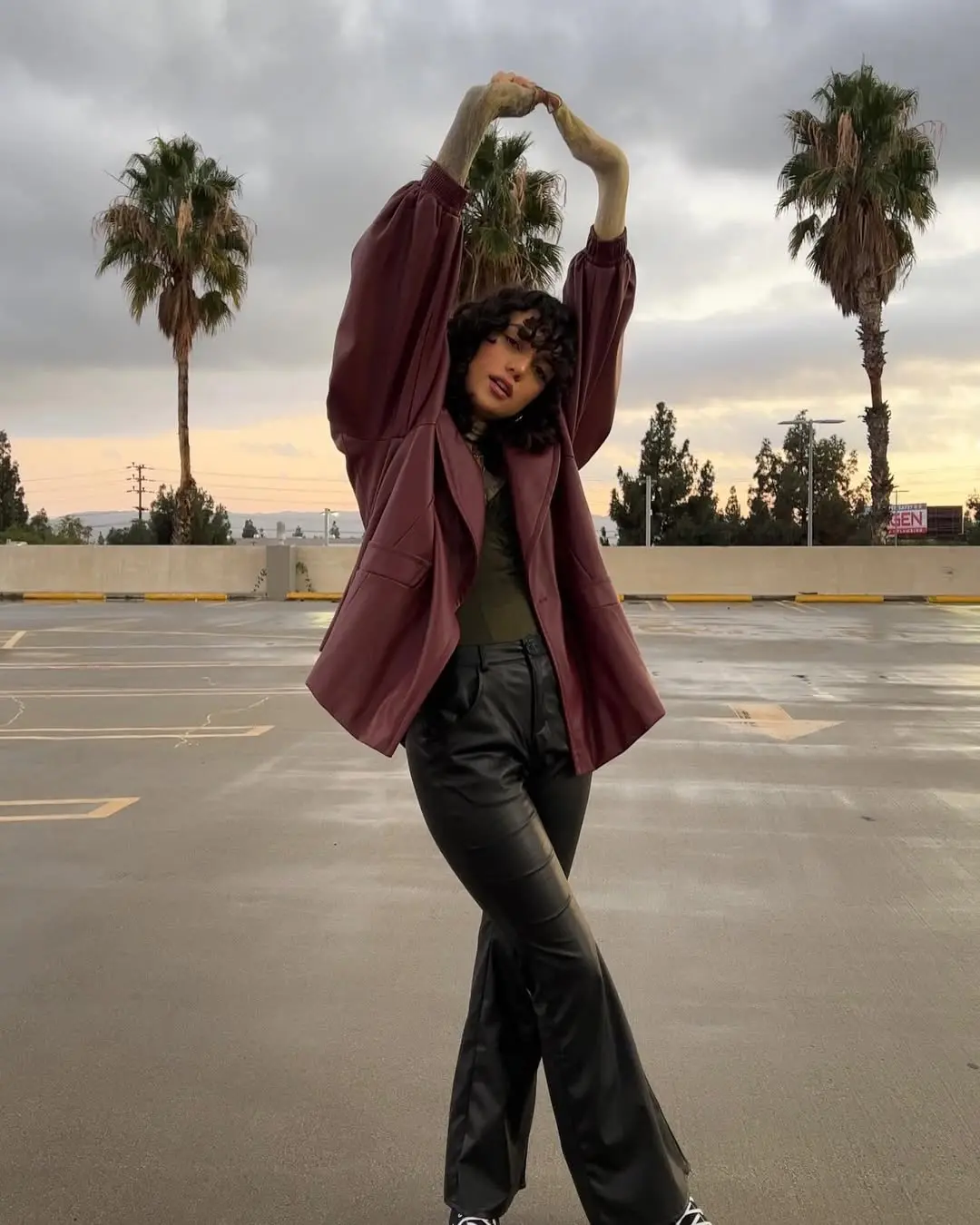 Edgy burgundy leather jacket ensemble in urban setting