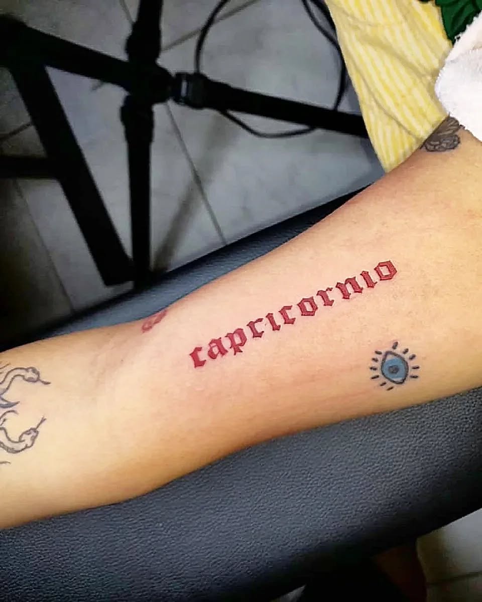 Stunning Red Capricorn Lettering Tattoo