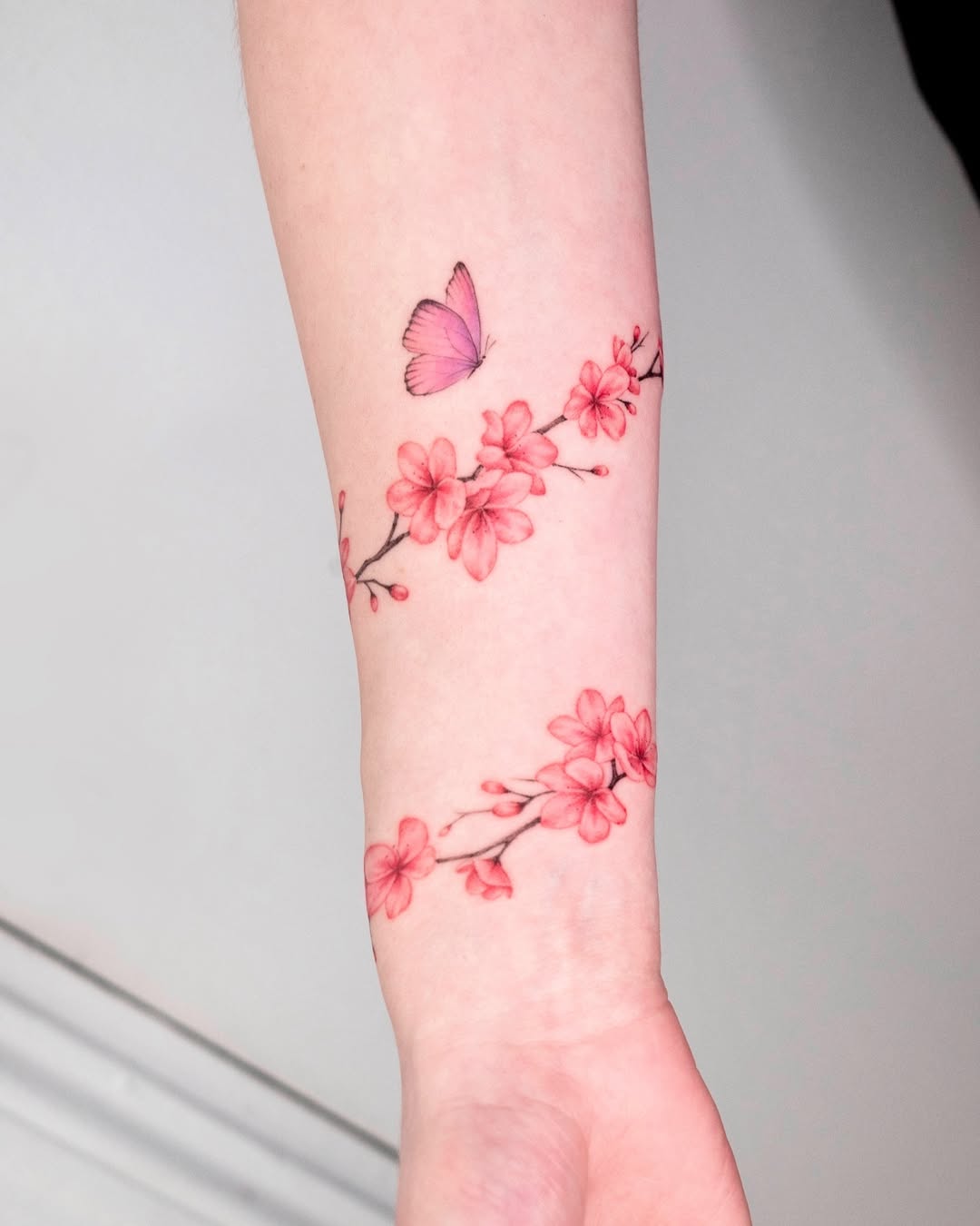 Delicate cherry blossom tattoo with a butterfly