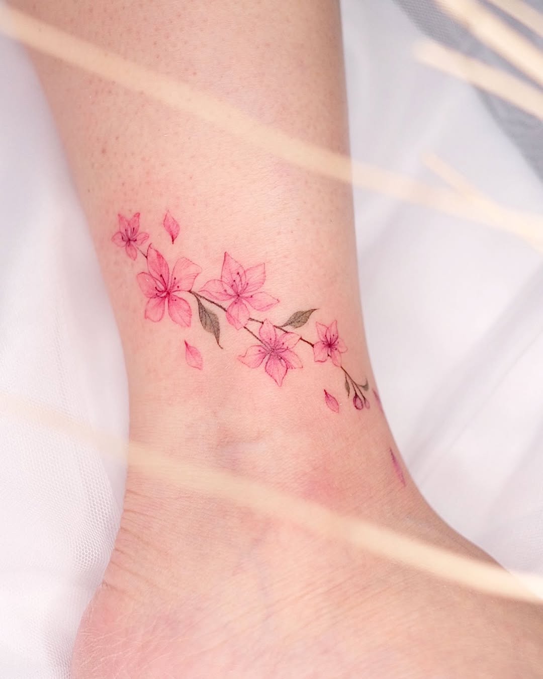 Delicate cherry blossom tattoo on the ankle