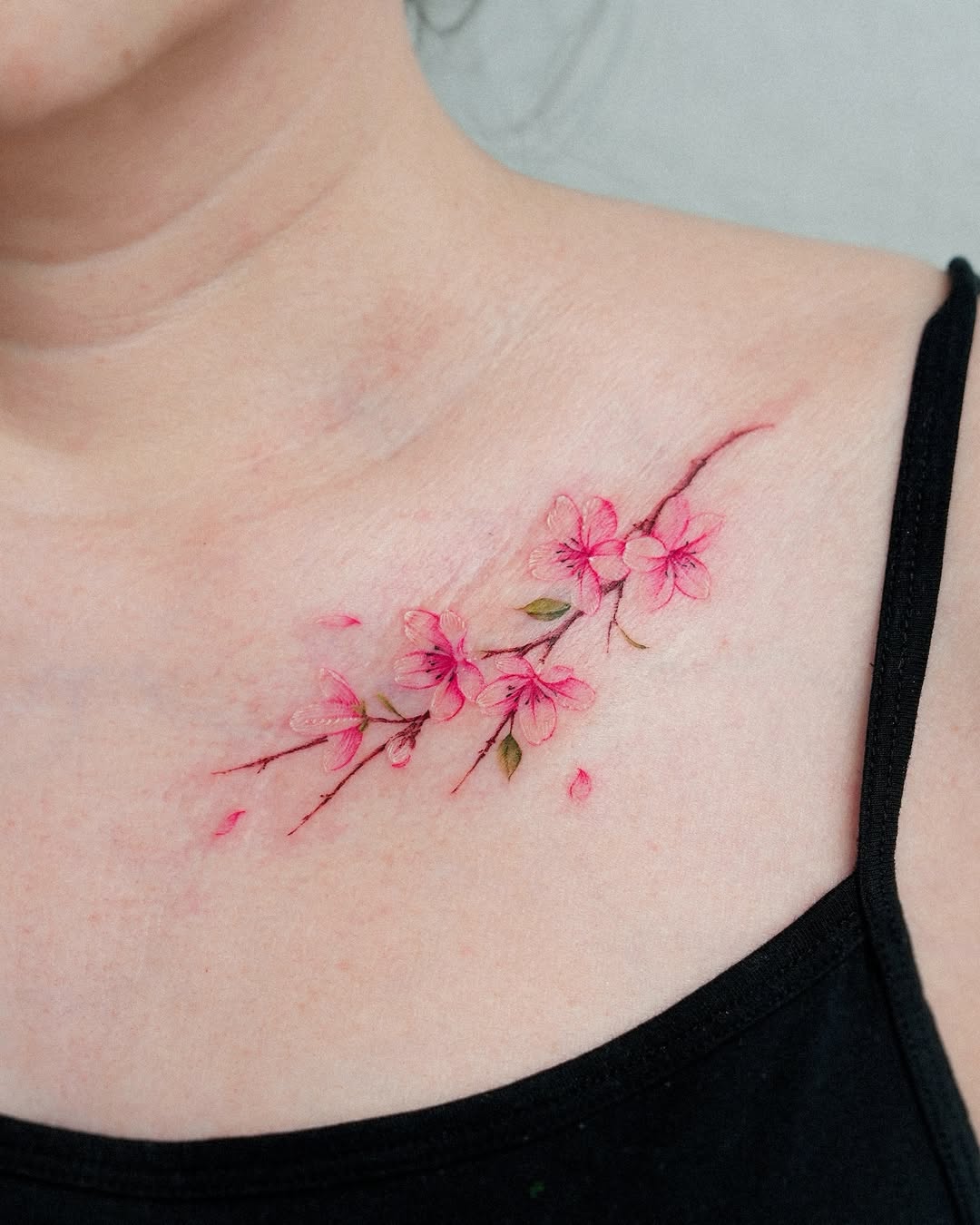 Delicate cherry blossom tattoo on collarbone