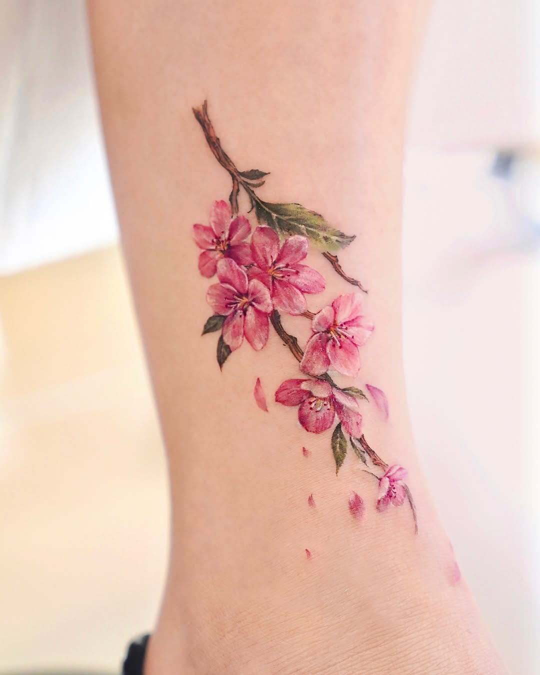 Elegant cherry blossom branch tattoo design on ankle