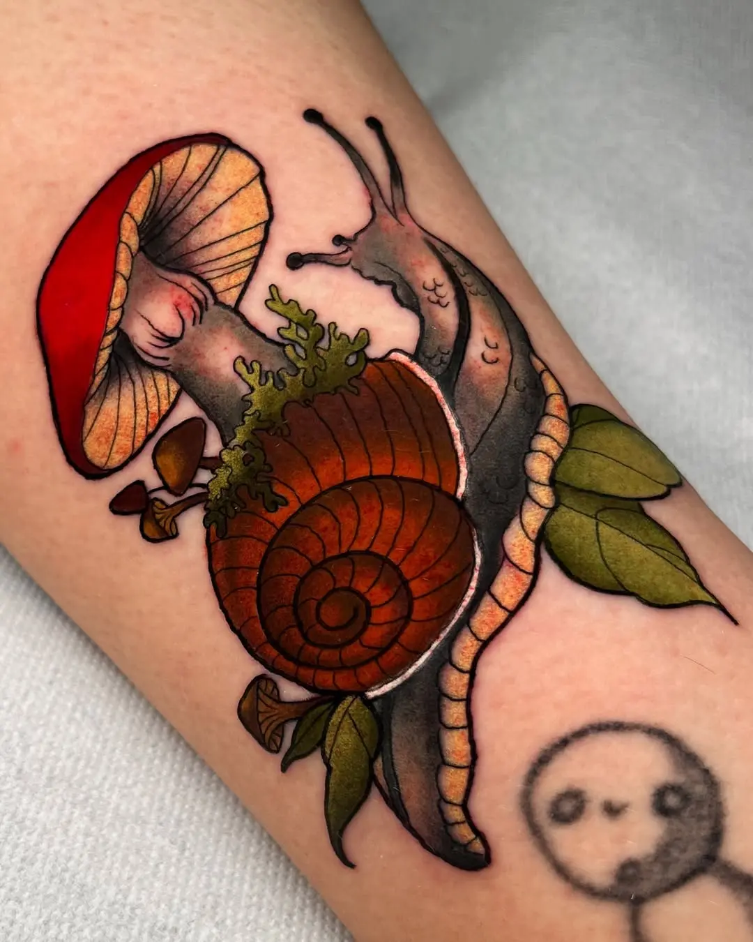 Whimsical mushroom and snail tattoo design
